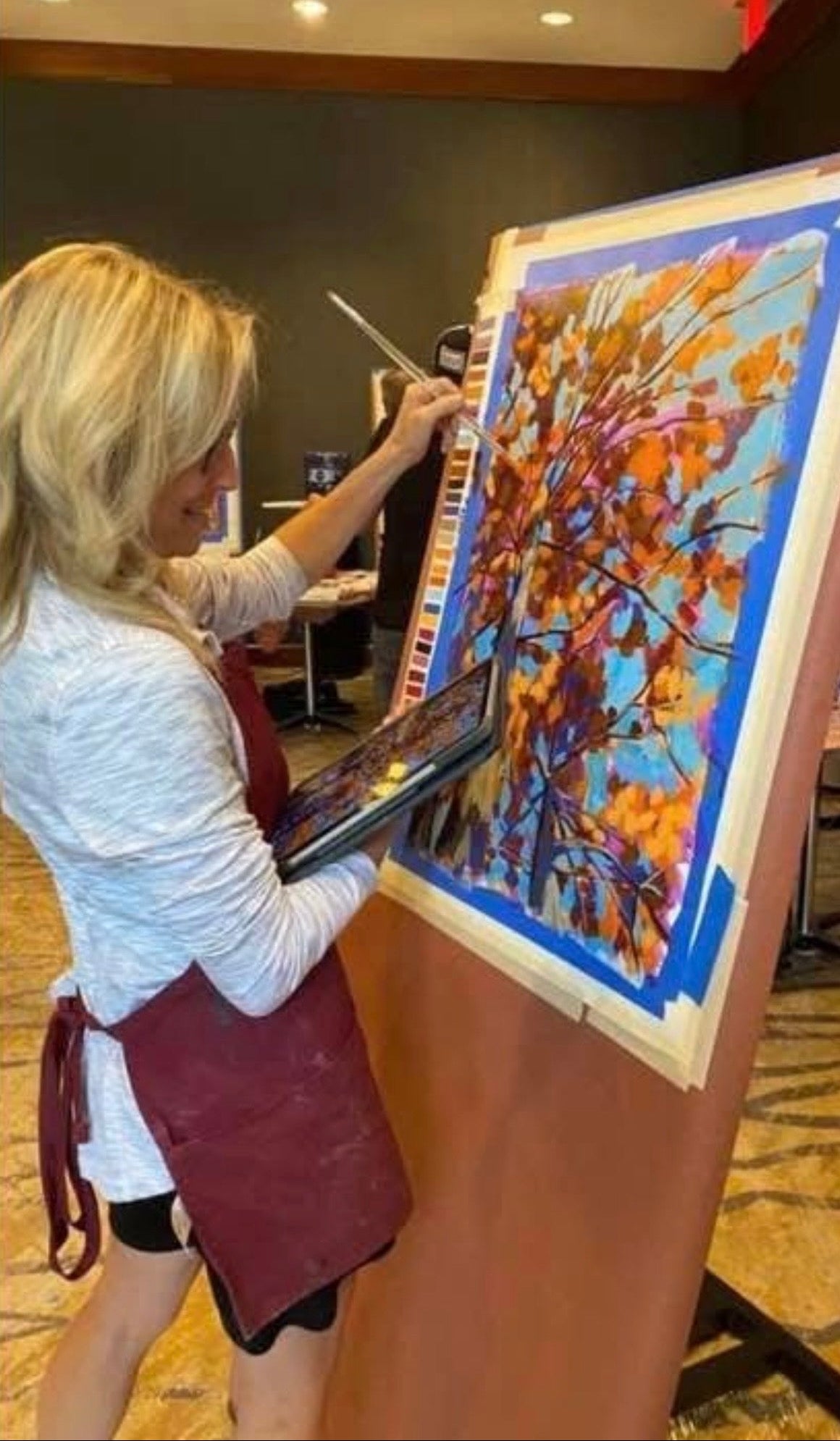 Jana painting a colorful abstract artwork at an event.
